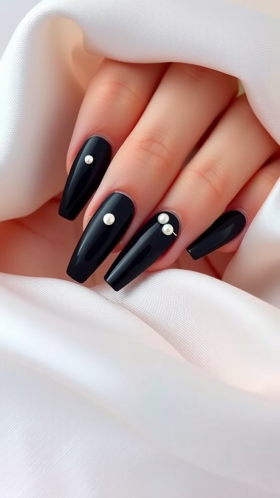 Elegant black nails adorned with pearls on a soft white fabric.
