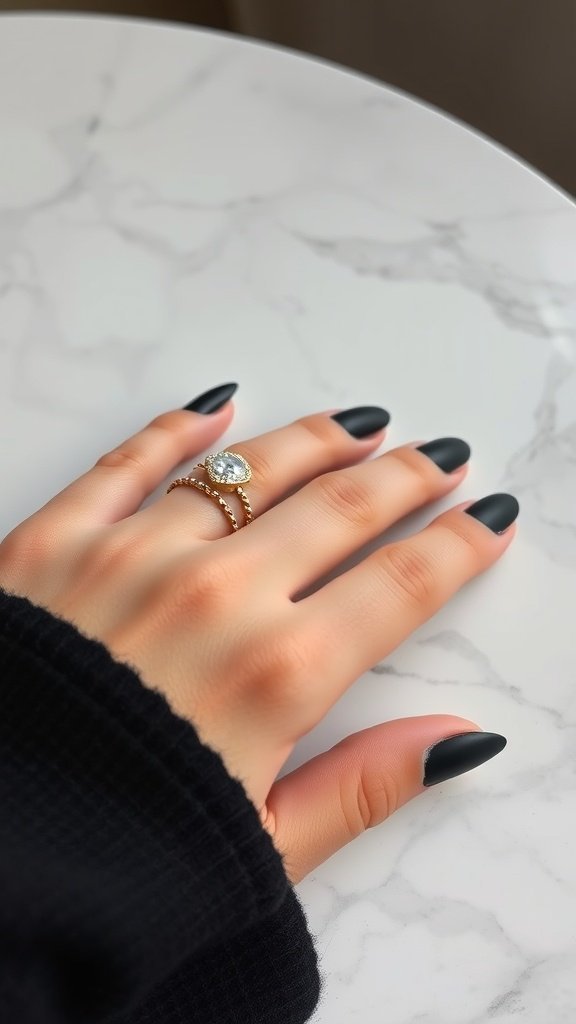 A close-up of hands with matte black nails resting on a marble surface