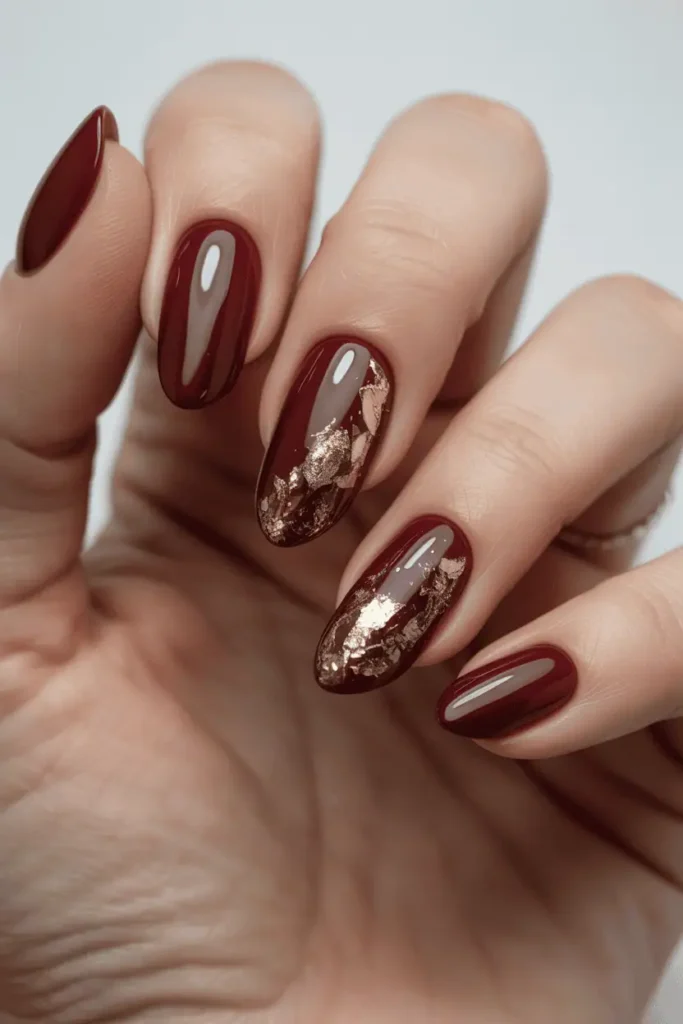 Burgundy nails with gold foil flakes accent.