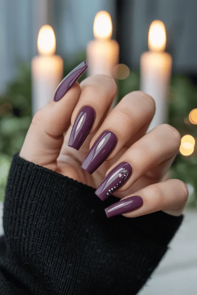 Glossy plum coffin nails styled with dark scarf and candlelight background.
